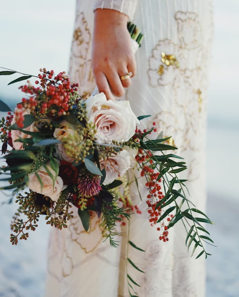 Blush bouquet held against a beaded gown