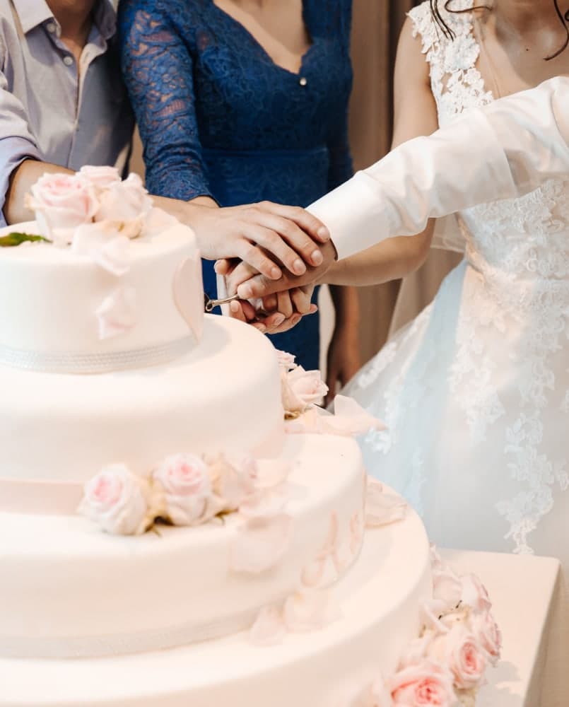 Hands meeting over a rose-covered cake