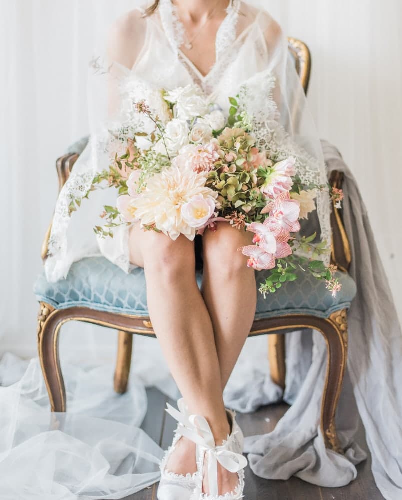 Blush and ivory bouquet held in the lap of a seated bride