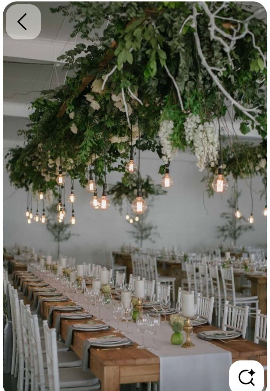 Reception table beneath hanging florals and warm lights